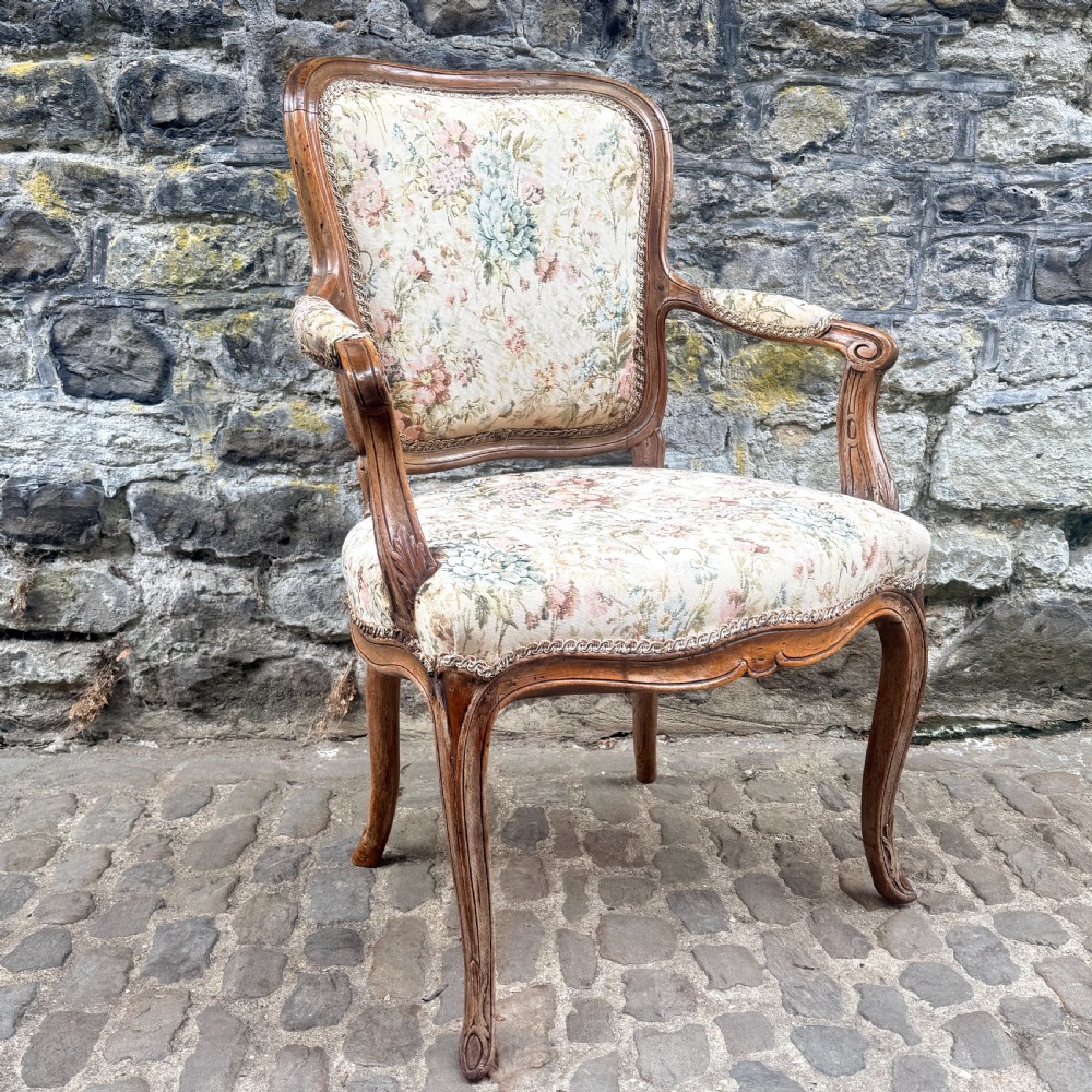 A Louis XV French provincial wooden armchair with carved cabriole legs and floral tapestry upholstery across the seat, backrest, and armrests. View VI