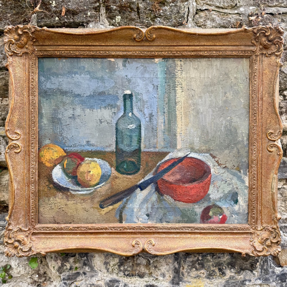 An early twentieth-century post-impressionist oil painting depicting a tabletop still life with a glass bottle, fruit, and a red bowl, enclosed within a carved swept gilt frame. View VI
