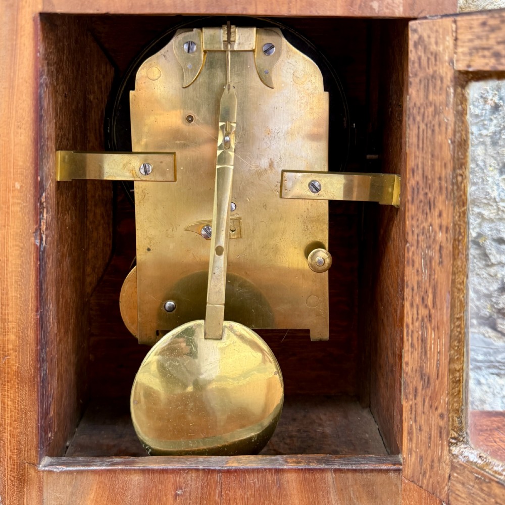 A Regency mahogany library clock featuring brass floral inlay, a pineapple finial, brass ball feet, and a white dial signed George Miles London. View VI