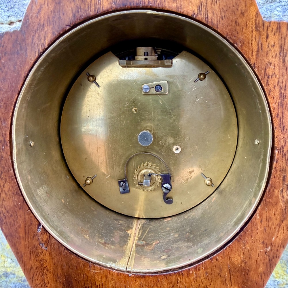 An Art Nouveau inlaid mahogany mantel clock featuring foliate marquetry, a white enamel dial with Roman numerals, and brass bun feet. View V