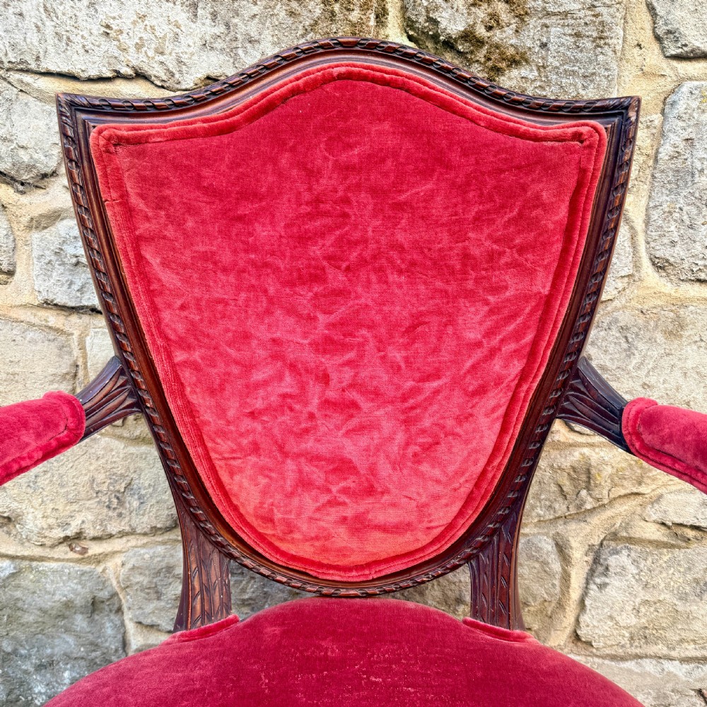 A Sheraton Revival mahogany desk chair with red velvet upholstery, a shield back, and fluted front legs. View VI