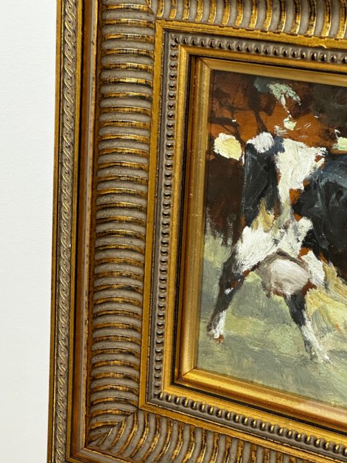 fig 2. An impressionist oil painting depicting a black and white Friesian cow grazing in a field, set within a heavily moulded gilt frame.