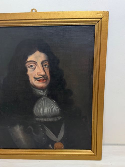 fig 4. A 19th-century framed oil portrait depicting King Charles II wearing armour, a white lace cravat, and the Order of the Garter medallion against a dark background.