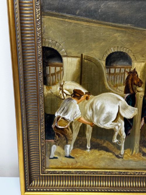 fig 7. A horizontal oil painting depicting grooms tending to horses inside a stable block, housed within a fluted gilt wood frame.