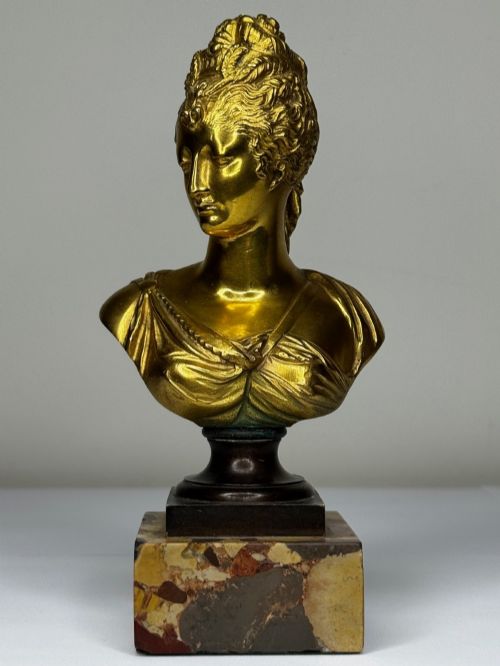fig 1. A 19th-century gilt bronze bust portrait of Diana de Poitiers featuring an ornate hairstyle and classical drapery, mounted on a dark socle and square variegated marble base.