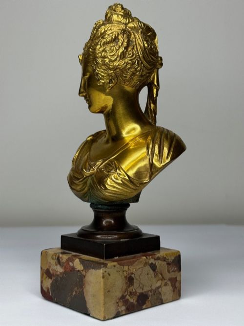 fig 2. A 19th-century gilt bronze bust portrait of Diana de Poitiers featuring an ornate hairstyle and classical drapery, mounted on a dark socle and square variegated marble base.