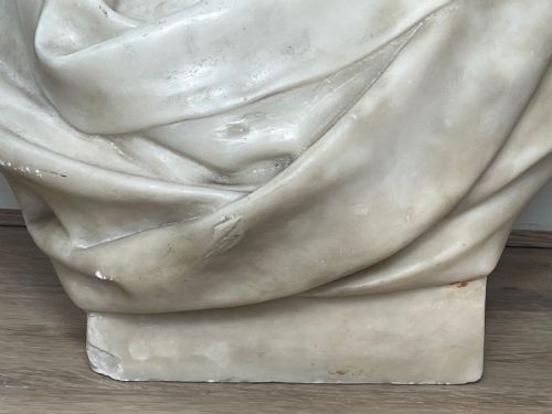 fig 3. A carved off-white marble bust depicting a bald male figure with a prominent moustache wearing classical draped fabric across the shoulders.