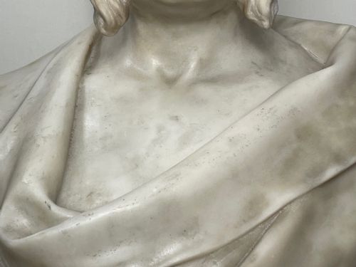 fig 6. A carved off-white marble bust depicting a bald male figure with a prominent moustache wearing classical draped fabric across the shoulders.