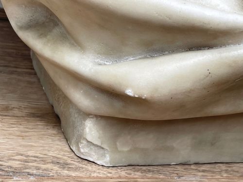fig 13. A carved off-white marble bust depicting a bald male figure with a prominent moustache wearing classical draped fabric across the shoulders.