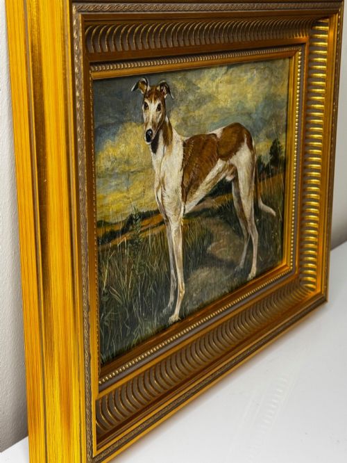 fig 5. An antique Edwardian oil painting depicting a tan and white lurcher dog in a landscape, set within an ornate gilded frame.
