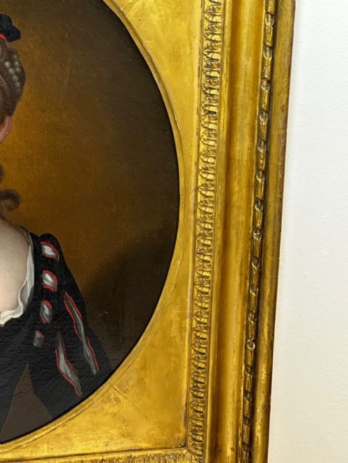 fig 4. An early 18th-century oil portrait of a young woman wearing a dark gown with slashed sleeves, presented in a square giltwood frame with an oval spandrel.