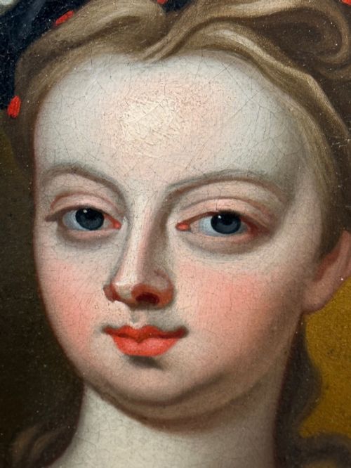 fig 7. An early 18th-century oil portrait of a young woman wearing a dark gown with slashed sleeves, presented in a square giltwood frame with an oval spandrel.