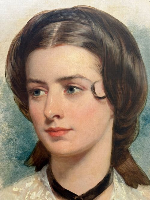 fig 1. A Victorian oil painting on canvas depicting a young woman with dark hair tied with a black ribbon, displayed within an intricate pierced gold gilt frame with an oval aperture.
