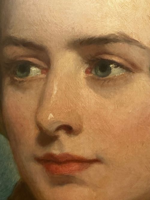 fig 6. A Victorian oil painting on canvas depicting a young woman with dark hair tied with a black ribbon, displayed within an intricate pierced gold gilt frame with an oval aperture.