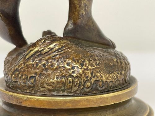 fig 1. A patinated bronze sculpture depicting a young girl carrying two large woven baskets on a rounded base.