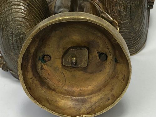 fig 3. A patinated bronze sculpture depicting a young girl carrying two large woven baskets on a rounded base.