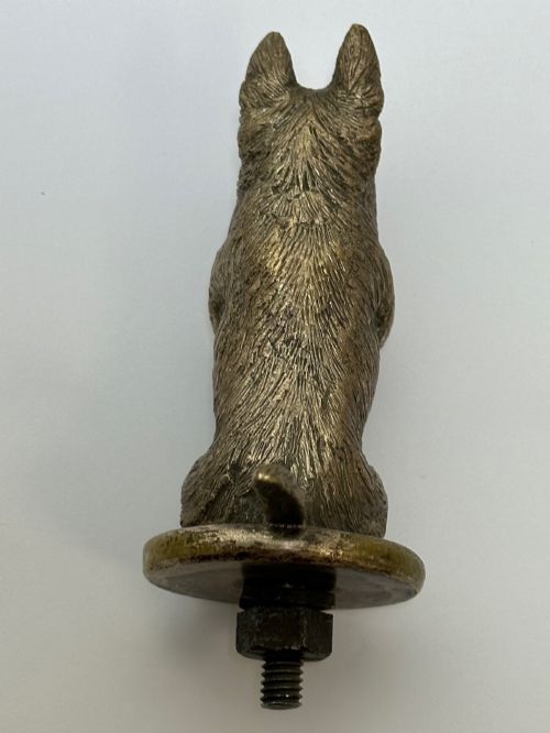 fig 1. A cast bronze car mascot depicting a Scottish Terrier sitting in a begging pose mounted on a small circular base with a threaded bolt.