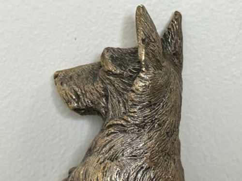 fig 2. A cast bronze car mascot depicting a Scottish Terrier sitting in a begging pose mounted on a small circular base with a threaded bolt.