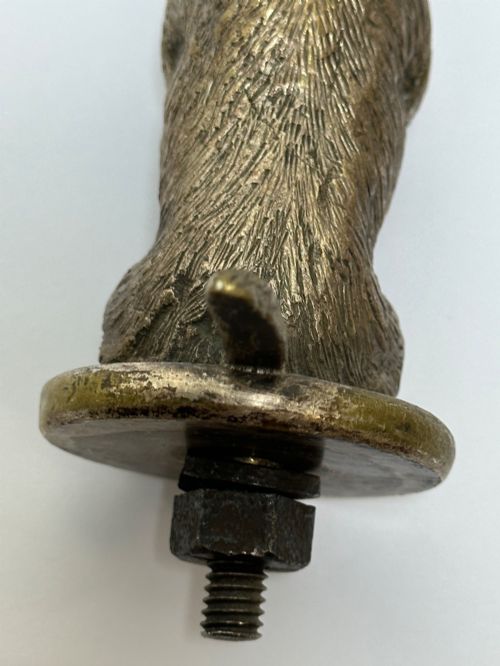 fig 6. A cast bronze car mascot depicting a Scottish Terrier sitting in a begging pose mounted on a small circular base with a threaded bolt.