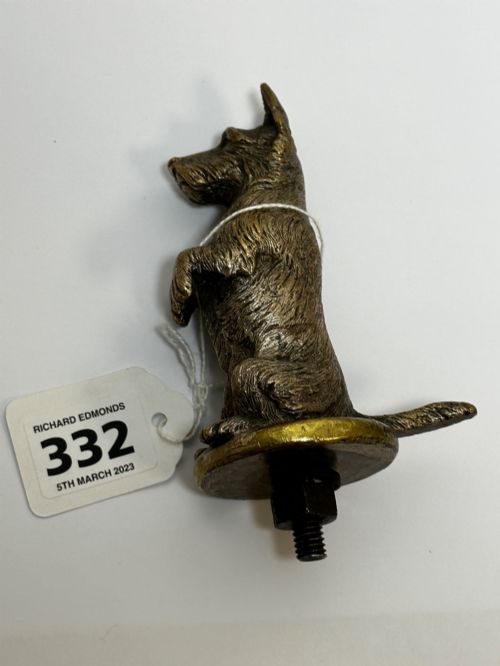 fig 8. A cast bronze car mascot depicting a Scottish Terrier sitting in a begging pose mounted on a small circular base with a threaded bolt.