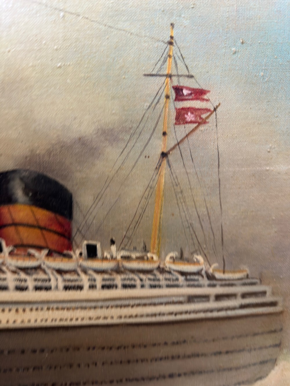 An oil painting depicting the RMS Queen Mary ocean liner sailing across blue waters under a cloudy sky, framed in a moulded gold gilt border. View XVII