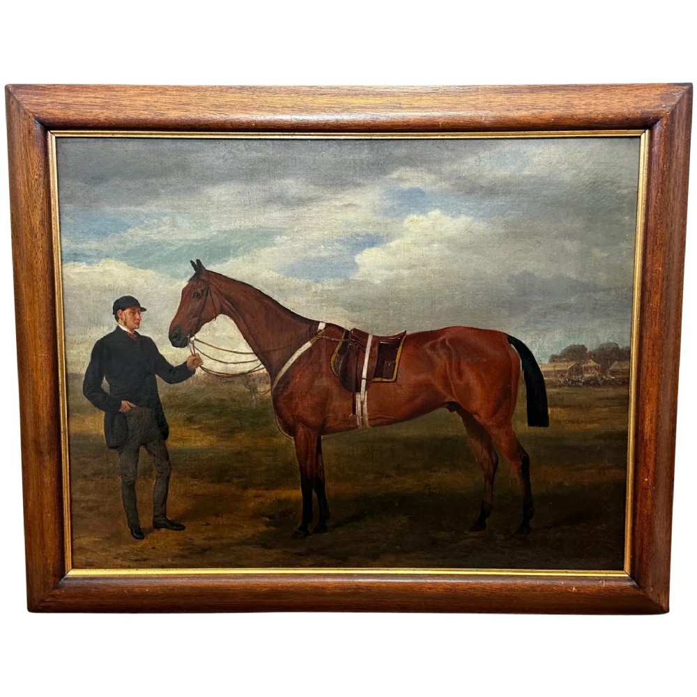 A 19th-century British oil painting depicting a saddled bay hunter horse and groom standing in a landscape, set within a timber frame.