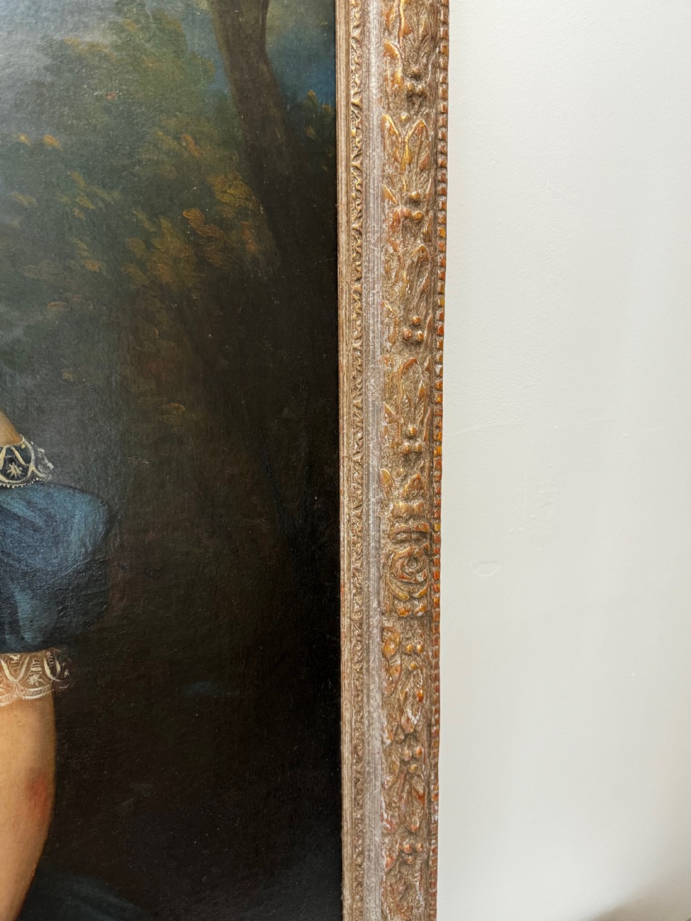 A Victorian oil portrait depicting a young girl in a dark blue off-the-shoulder dress holding a bonnet, accompanied by a small white dog, framed in an ornate gilded border. View IV