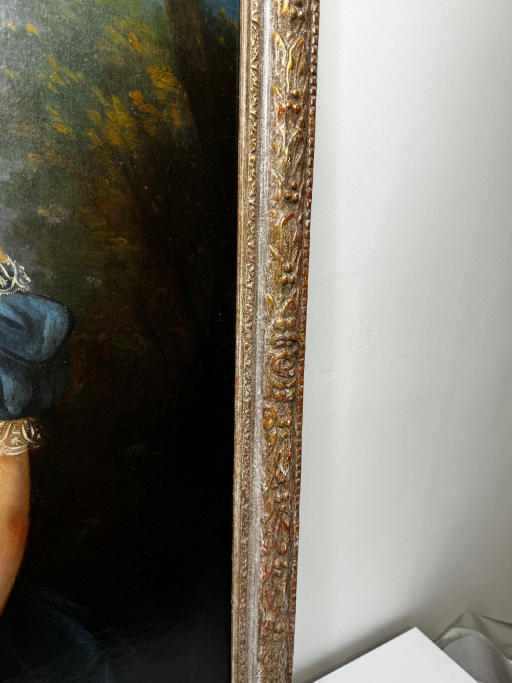 A Victorian oil portrait depicting a young girl in a dark blue off-the-shoulder dress holding a bonnet, accompanied by a small white dog, framed in an ornate gilded border. View V