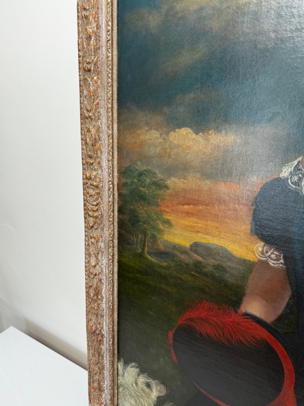 A Victorian oil portrait depicting a young girl in a dark blue off-the-shoulder dress holding a bonnet, accompanied by a small white dog, framed in an ornate gilded border. View VI