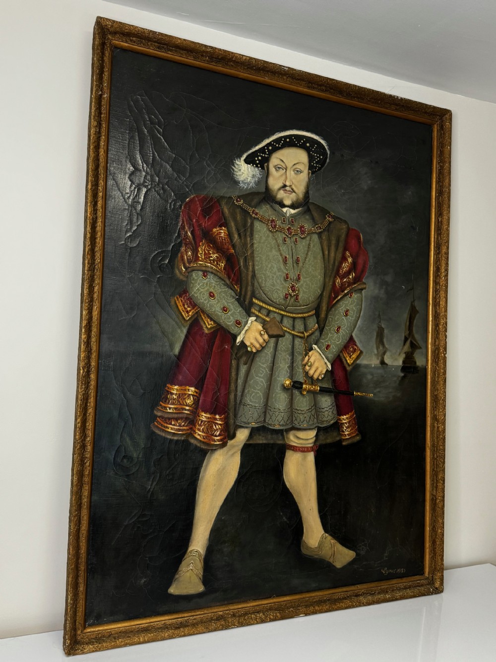 A large oil painting in a gilded frame depicting King Henry VIII standing in Tudor costume with jewels, dagger, and feathered cap against a dark backdrop. View II