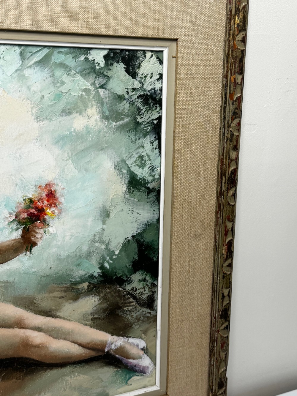 A framed mid-century oil painting depicting a seated ballerina in a white tutu holding a small bouquet of flowers against a textured soft green background. View III