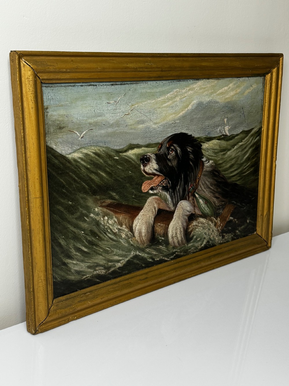 An antique oil painting depicting a Saint Bernard dog swimming in sea waves while clinging to a wooden spar, set within a gilded wooden frame. View VIII