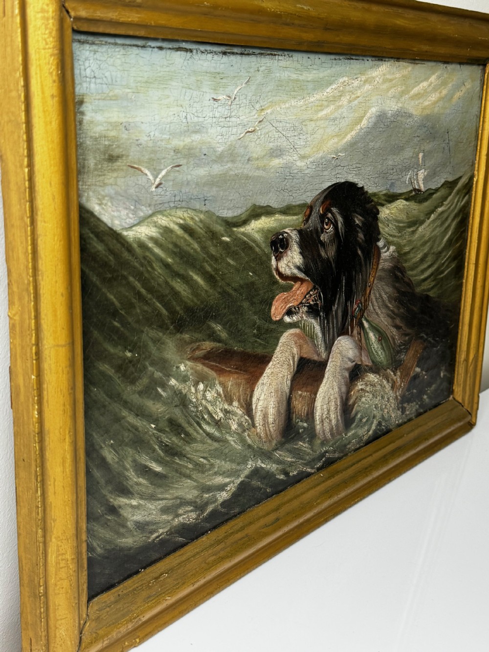 An antique oil painting depicting a Saint Bernard dog swimming in sea waves while clinging to a wooden spar, set within a gilded wooden frame. View IX