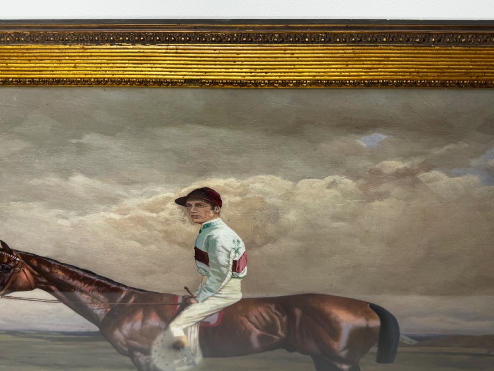 A nineteenth-century oil painting depicting a brown thoroughbred horse with a jockey in white and red silks, framed in a ribbed gold-leaf frame. View XV