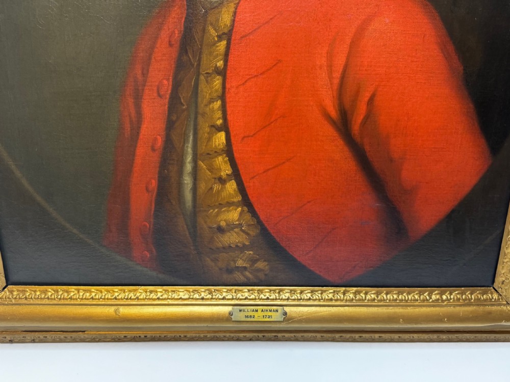 An 18th-century oil portrait painting depicting a gentleman in a red coat and white cravat housed within a moulded giltwood frame. View IV
