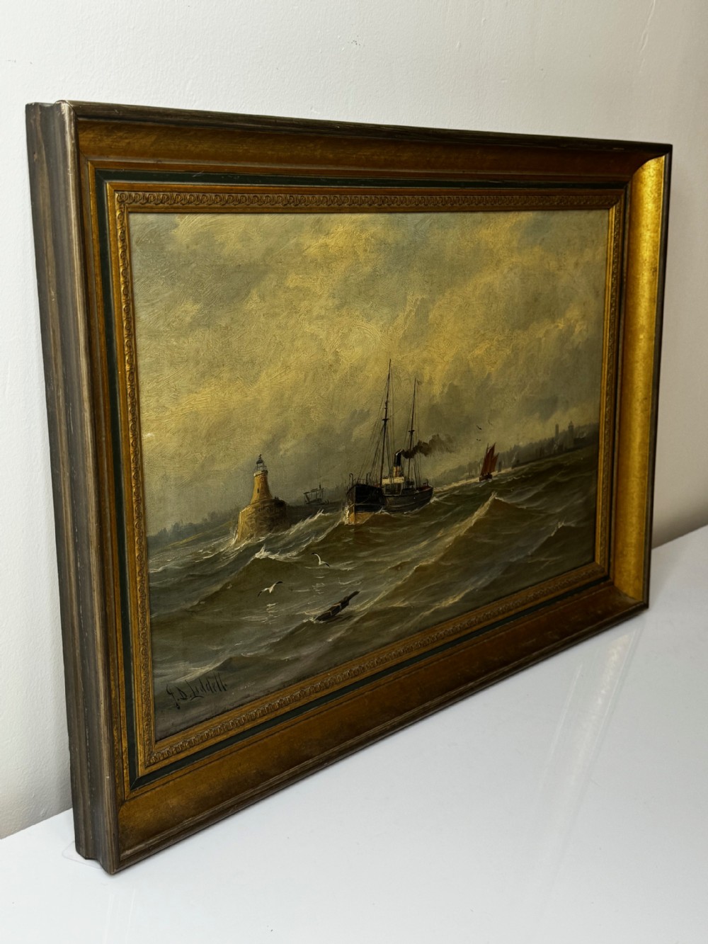 An antique framed oil painting depicting a steam pilot boat navigating choppy grey waters near a lighthouse under an overcast sky. View XXII