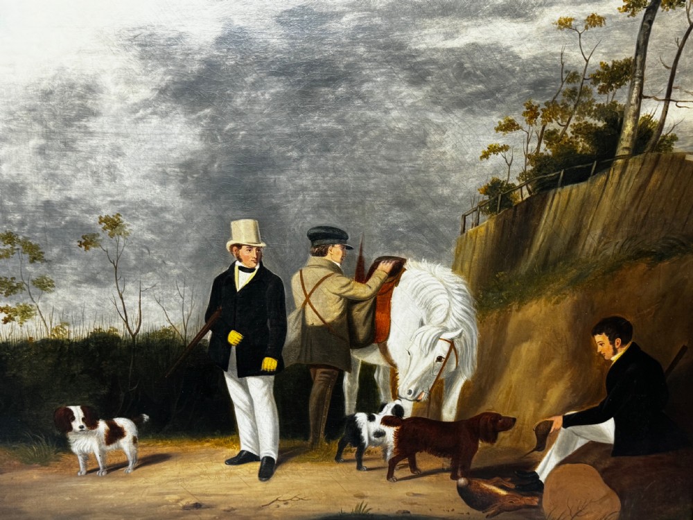 An antique oil painting in a decorative gilded frame depicting three men with hunting dogs and a white horse in a countryside setting. View XI