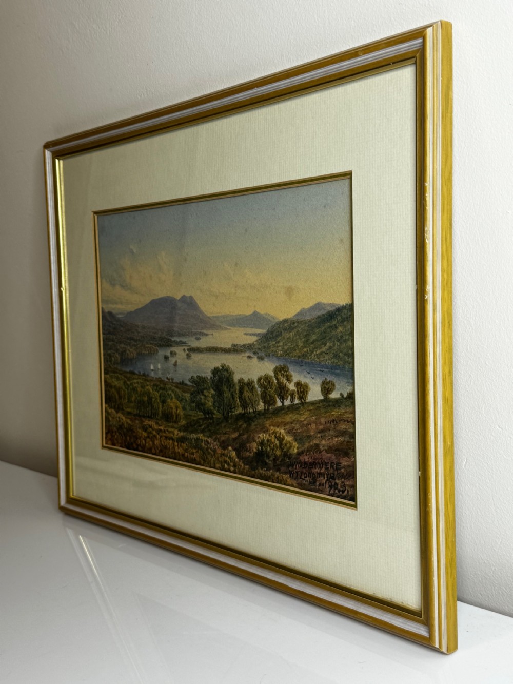 A framed Edwardian watercolour painting depicting an elevated landscape view over Lake Windermere surrounded by hills and trees. View XI