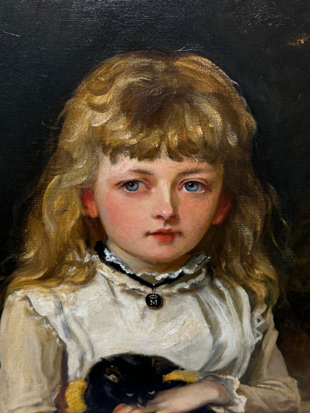 A Victorian oil portrait on canvas depicting a young girl with blonde hair holding a black cat, presented in a carved gold-coloured frame. View XXV