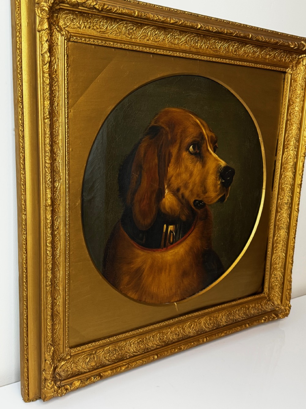 A Victorian oil painting depicting the head profile of a brown hound set inside a circular aperture within a heavy gold gilt frame. View VII