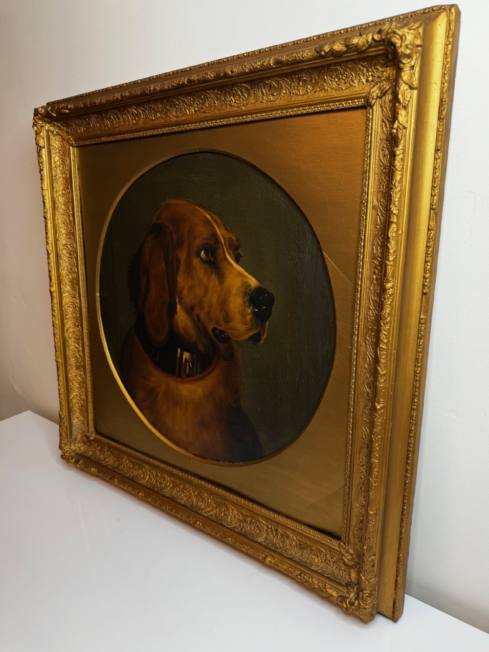A Victorian oil painting depicting the head profile of a brown hound set inside a circular aperture within a heavy gold gilt frame. View XXX