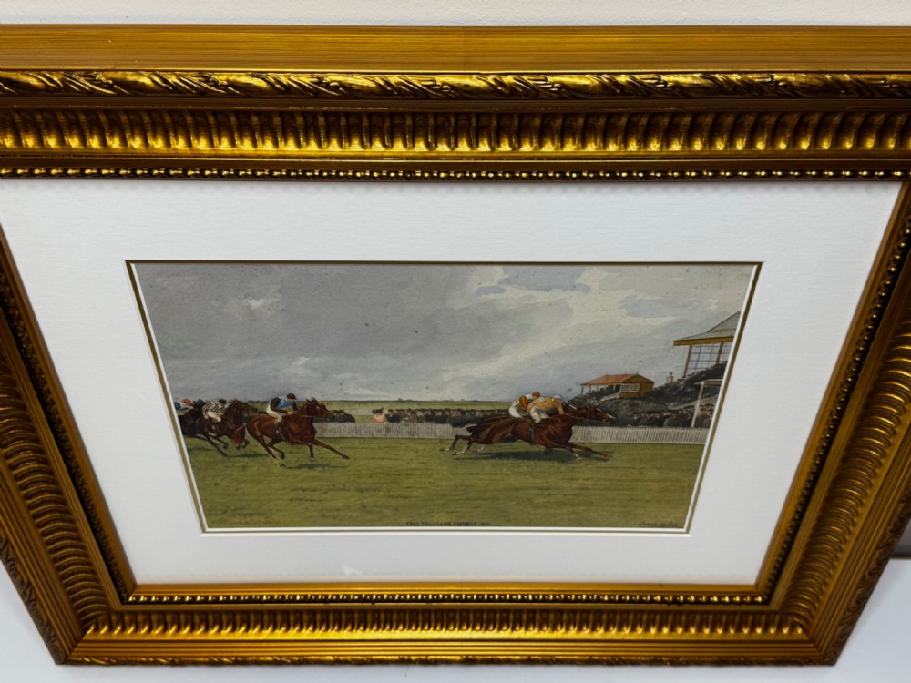 A framed British equestrian painting depicting racehorses and jockeys galloping on a green racetrack at Newmarket within a fluted gold-gilt frame. View XII