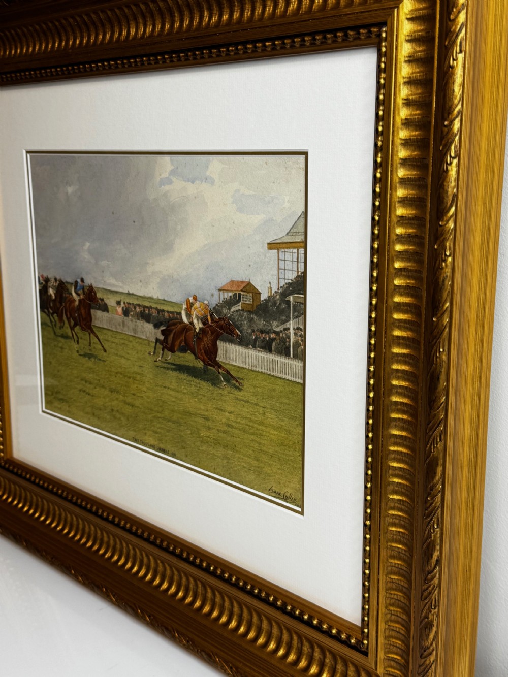 A framed British equestrian painting depicting racehorses and jockeys galloping on a green racetrack at Newmarket within a fluted gold-gilt frame. View XIV