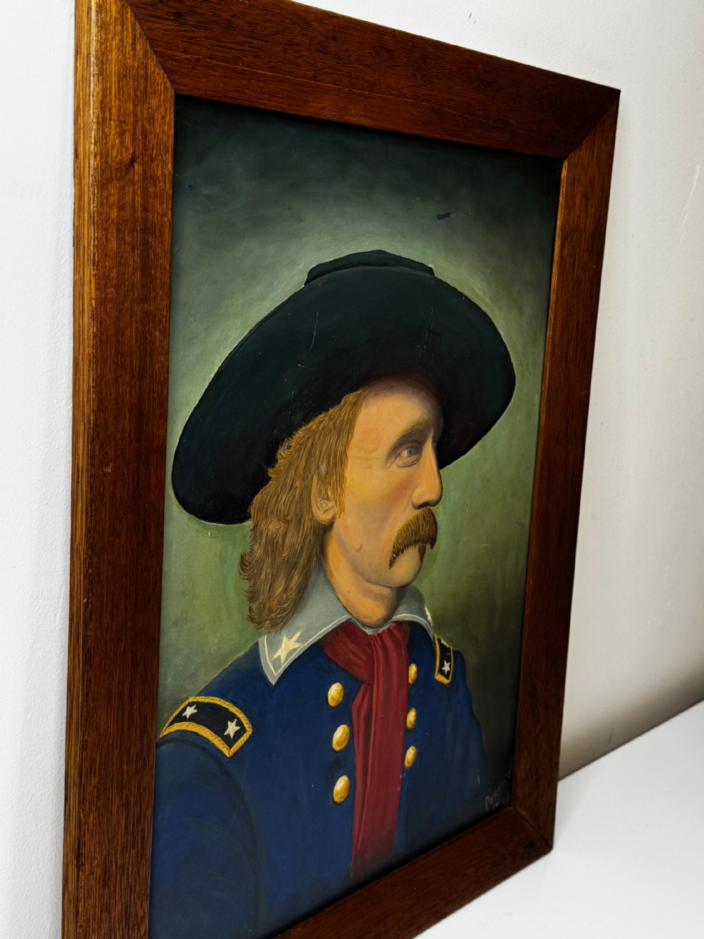 A framed oil painting portraying General George Custer in profile wearing a blue uniform with gold stars and a black hat. View V
