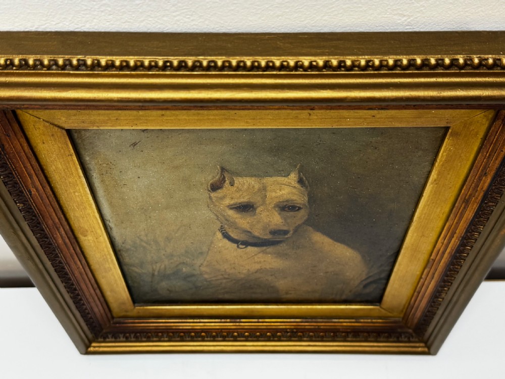 An antique oil painting depicting a white English terrier set within an ornate gilded wooden frame. View IX