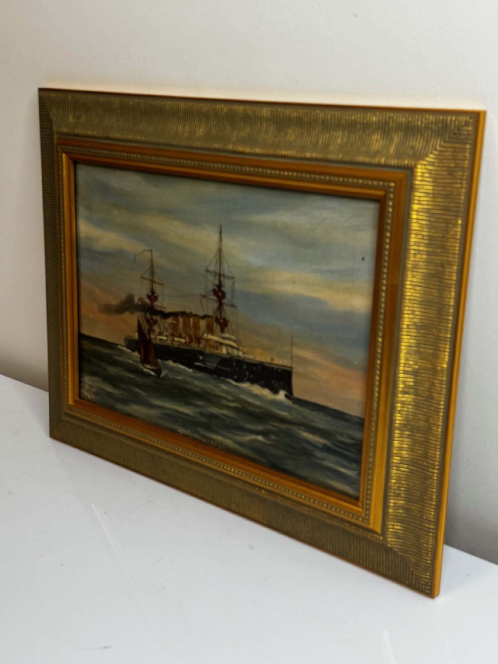 An oil painting depicting the Royal Navy cruiser HMS Powerful sailing across open waters with smoke billowing from its funnels under a sunset sky, housed in a gilt frame. View VI