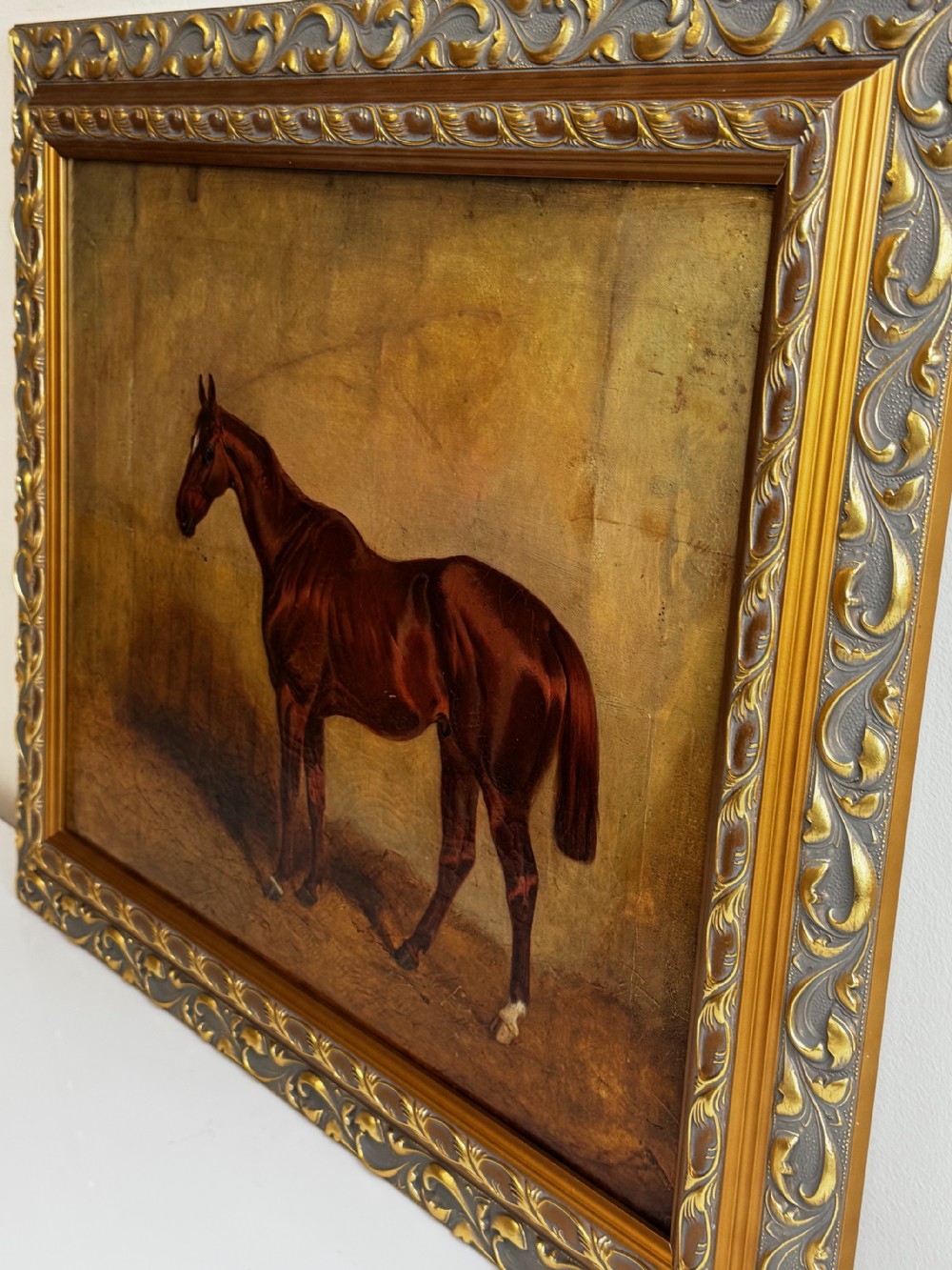 An antique oil painting depicting a standing chestnut brown hunter horse inside a stable, housed within an ornate gilded frame. View III