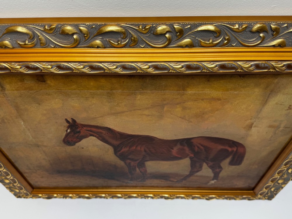 An antique oil painting depicting a standing chestnut brown hunter horse inside a stable, housed within an ornate gilded frame. View V