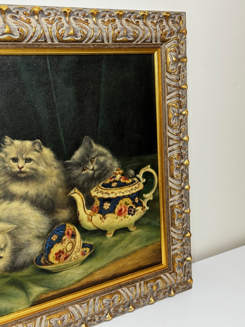 A framed oil painting featuring six fluffy grey and silver Persian kittens arranged around a woven basket and a decorated porcelain teapot. View III