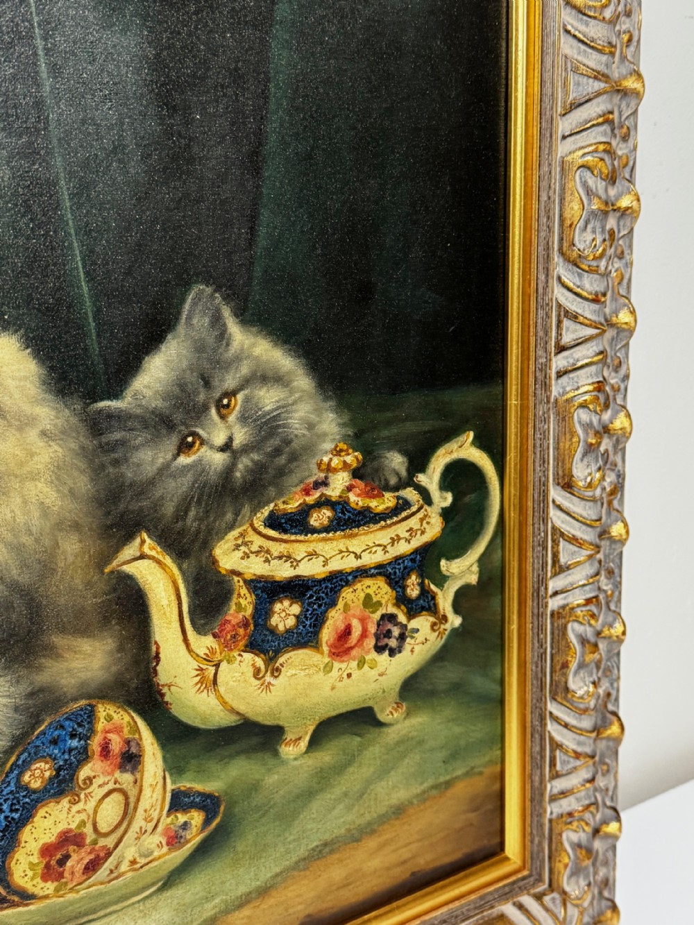 A framed oil painting featuring six fluffy grey and silver Persian kittens arranged around a woven basket and a decorated porcelain teapot. View IV